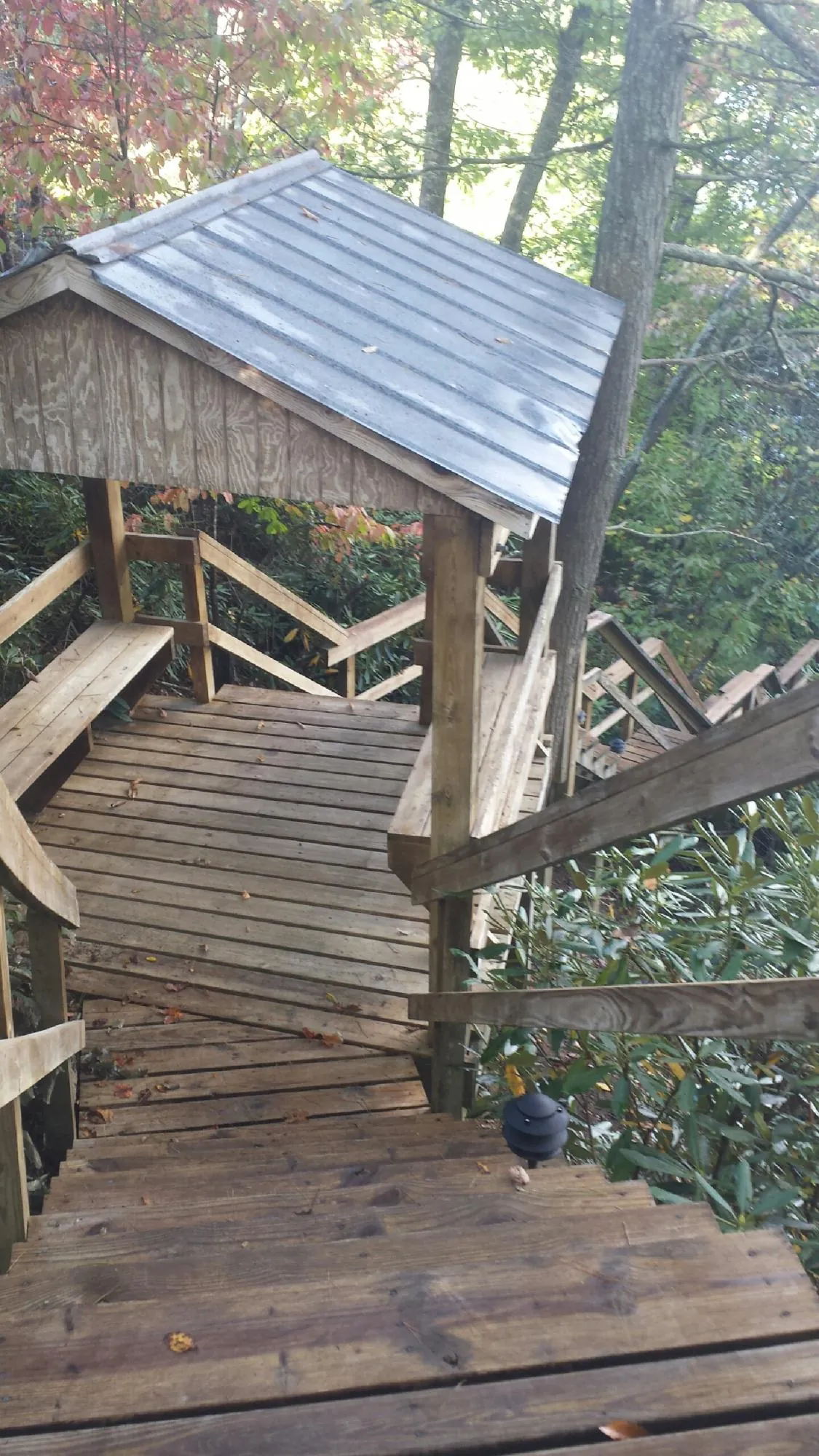 Metal roofed shelter over wooden steps on a wooded walkway — Skylight Repair & Installation work by our crew in Saltsburg