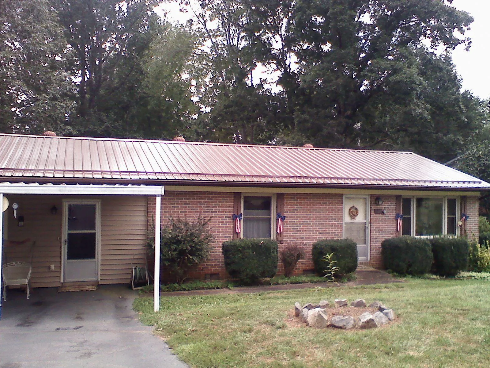 Bronze metal roof and carport on a brick ranch home — Roof Repair work by our crew in Saltsburg
