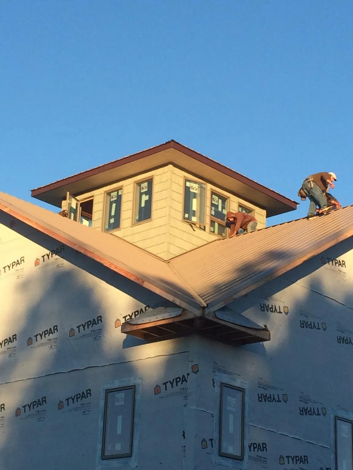 Roofers working around a rooftop cupola on a new metal roof at sunset — Roof Waterproofing in Saltsburg by Roofing Brothers